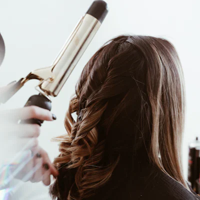 A stylist curling long brunette hair